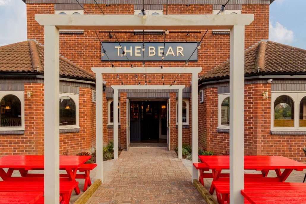 The Bear entrance with red bench dining tables